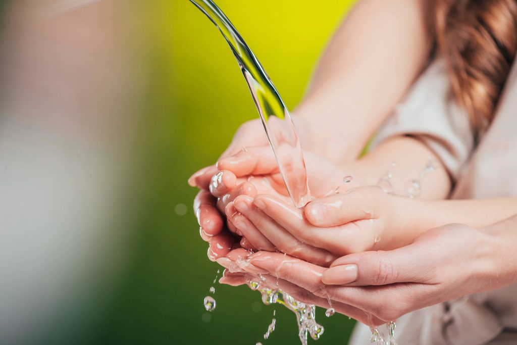 Selective focus of woman and child holding hands under flowing water